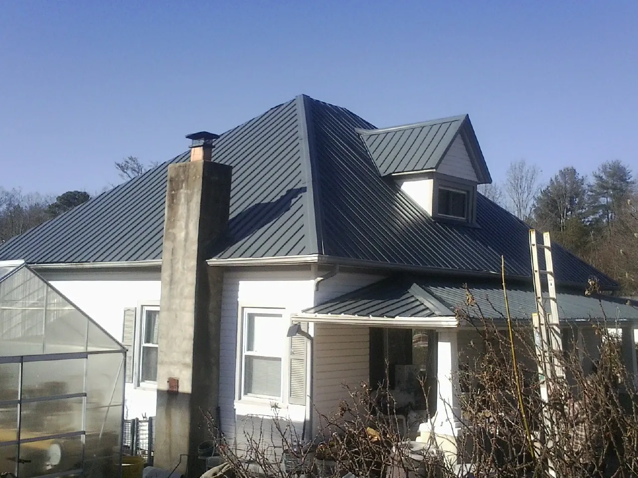 Dark blue standing seam metal roof on a white farmhouse with dormer — Slate & Tile Roof Repair by Roofing Brothers in Ceresco